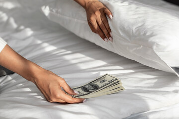 Black woman hiding money under pillow at home