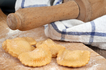 Préparation de raviolis sur une planche à découper  avec un rouleau à pâtisserie posé sur un torchon
