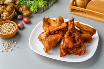 Ayam Goreng Ketumbar or Coriander Herbs Fried Chicken Served on white plate and isolated on gray background.