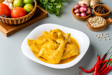 Indonesian Traditional cuisine : Ayam Gulai Padang. Ayam Gulai is a popular dish of chicken curry from Padang, West Sumatra. served on plate and isolated on gray background.