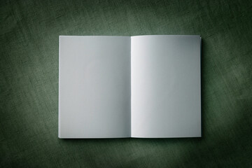 暗がりの中の開きの白いノートと緑の背景