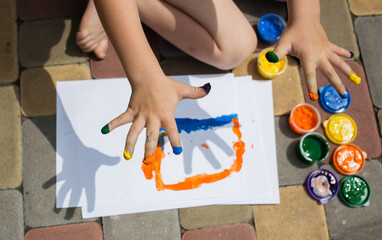 child draws with multi-colored finger paints. fingers are stained with paint. entertainment for child, development of creative abilities in children, rest with benefit
