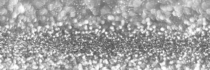 Silver sparkling glitter bokeh background, christmas texture. Holiday lights. Abstract defocused header. Wide screen wallpaper. Panoramic web banner with copy space for design