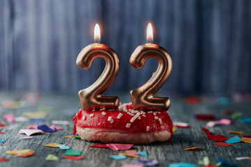 lit candles in the shape of number 22 in a cake