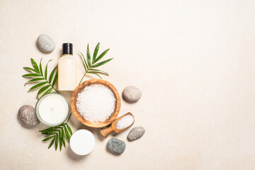Spa wellness background. Spa product composition with palm leaves, cosmetic and sea salt at stone table. Flat lay image with copy space.