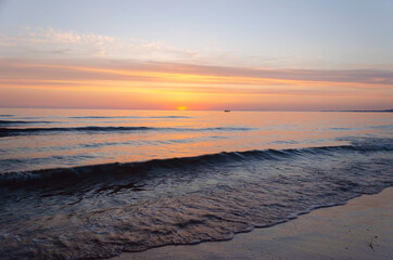 Obraz premium Fiery sunset on the sea. The silhouette of a ship is visible on the horizon