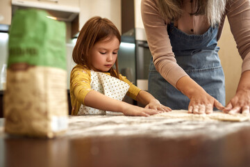 European little girl making dough with grandmother