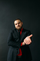 young man, business, sociable speaker, businessman, in a suit with a red shirt, in the studio on a black background.
