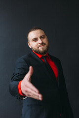 young man, business, sociable speaker, businessman, in a suit with a red shirt, in the studio on a black background.