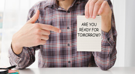 The man points to the paper with the are YOU READY text.