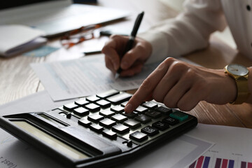 Tax accountant with calculator working at wooden table, closeup