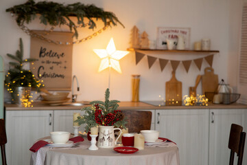Served table with candles and Christmas decoration in kitchen.