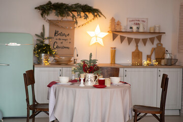 Served table with candles and Christmas decoration in kitchen.