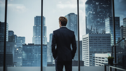 Thoughtful Young Businessman in a Perfect Tailored Suit Standing in His Modern Office Looking out...