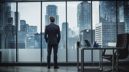 Successful Young Businessman in a Perfect Tailored Suit Standing in His Modern Office Looking out...