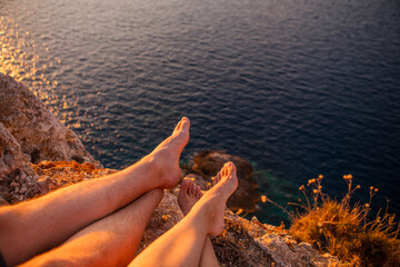 couple sitting on the cliff enjoying sunset