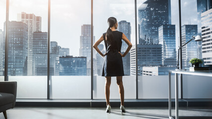 Successful Businesswoman in Stylish Dress Looking out of the Window at Big City in Downtown Area. Confident Female CEO Working on Financial Projects. Manager at Work Planning Marketing Campaign.