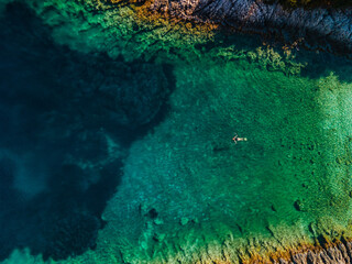 overhead view of woman floating on back in clear sea water