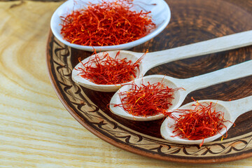 Saffron dry stamens in wooden spoons and bowls on a wooden table.