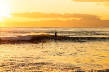 Fototapeta na wymiar 美しい夕陽を背にサーフィン
