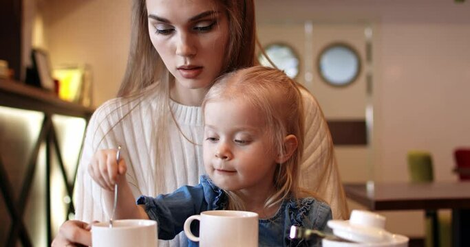 Mother and daughter are drinking tea in a cafe. Young family.