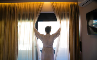 Woman opening curtains