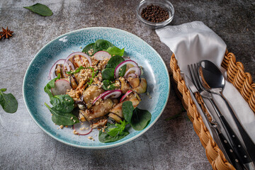 Serving a dish from a restaurant menu. Stuffed eggplants with onions, green spinach and walnuts on a plate against the background of a gray stone table