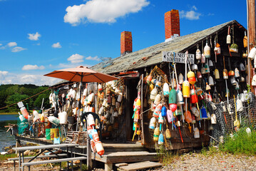 Fototapeta A lobster shack in Maine is decorated with numerous lobster buoys and a sign advising their food is fresh off the boat obraz