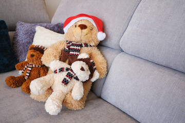 Teddy bear family wearing a Santa  Christmas hat on sofa in living room.