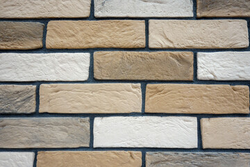 Multi-colored brick wall with dark gray seam.