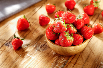 Fresh strawberries on a wooden table in the summer sunshine 