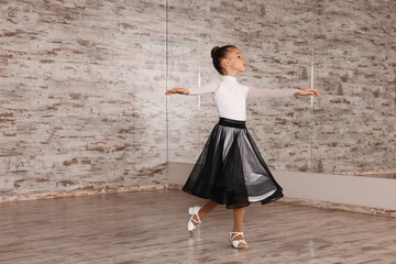 Adorable little girl dancing in studio, space for text