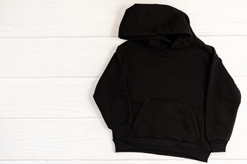 Black kid sweatshirt with hood on white background top view. Fashionable unisex clothing, hoodie,...