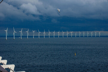 Eine Reihe Windräder im Meer mit Regenwolken
