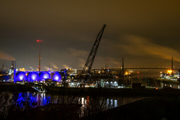 Blick auf den Hamburger Hafen bei Nacht mit lila beleuchteten Gastanks