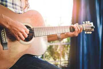 man playing acoustic guitar in music practice room He is happy to play music. The concept of playing live music and bands, performing shows. - obrazy, fototapety, plakaty