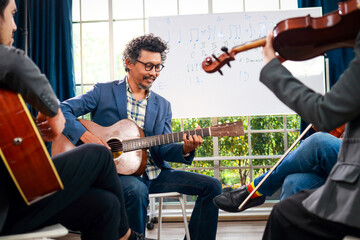 A group of Asian musicians playing guitar and violin sitting on classical music. They are fun and...
