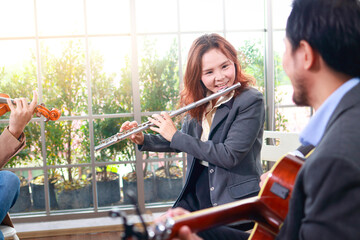A group of Asian musicians playing classical instruments, flute, violin and guitar. They play...