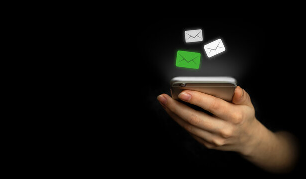 E-mail and social media. Hand using smartphone with new messages icon. Business and marketing concept, black background photo