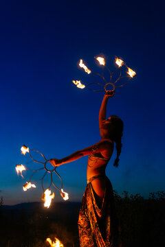 Woman with fire fans in darkness