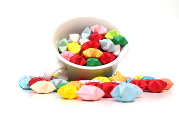 Colorful origami lucky stars spilling out of cup