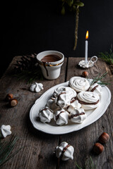 Meringue cookies with chocolate and almond cream and cup of hot chocolate, wrapped presents and natural winter decorations on old wooden table 