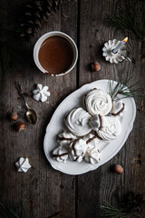 Meringue cookies with chocolate and almond cream and cup of hot chocolate, wrapped presents and natural winter decorations on old wooden table 