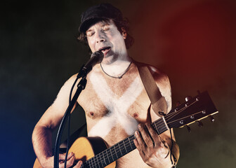 Obraz premium Musician singing and playing guitar at concert