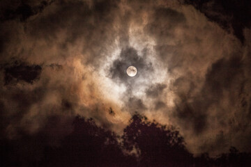 Fototapeta na wymiar Full moon peeking through the clouds.