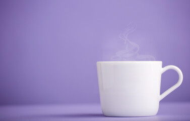 White ceramic cup of coffee or tea with hot steam, with a purple background (very peri).