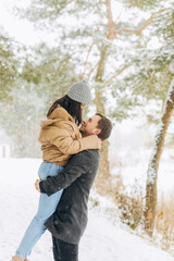 Fototapeta na wymiar Young couple kissing in a winter park near a pine tree