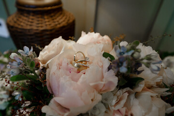 Wedding golden rings inside pink peony petals Three Elegant rings closeup Marriage concept Top view Bride and groom's wedding rings Bridal bouquet Cropped photo 