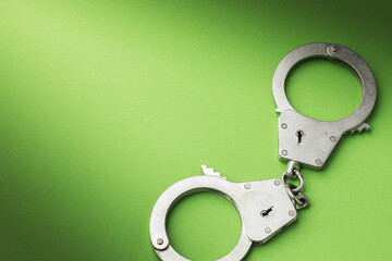 Handcuffs on a green background with copy space, top view