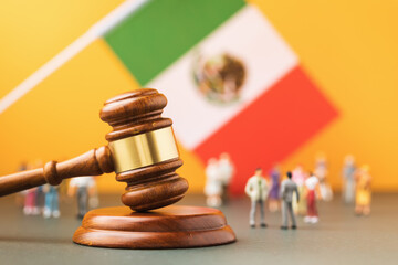 Wooden judge gavel, flag and plastic toy men on yellow background, Mexican society litigation...